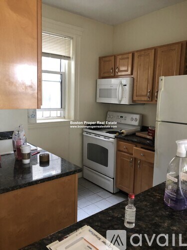 A kitchen with a black counter top and wooden cabinets.