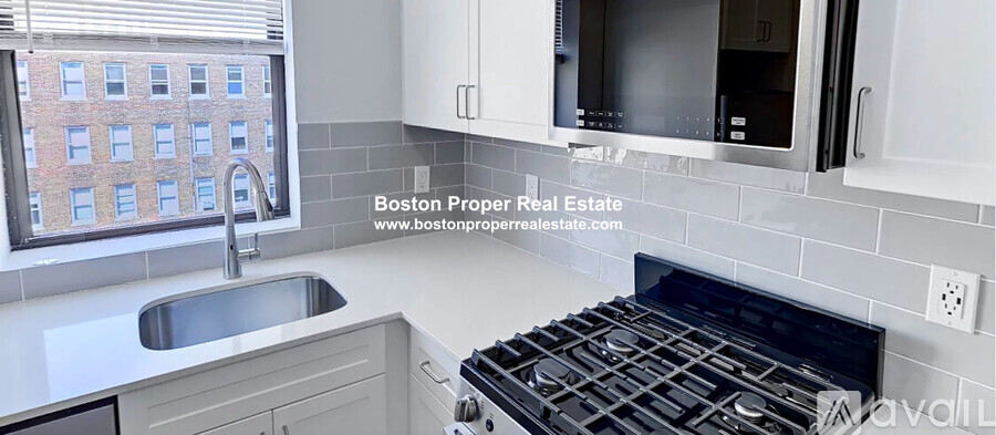 A modern kitchen with a stove top oven and a window overlooking a building.