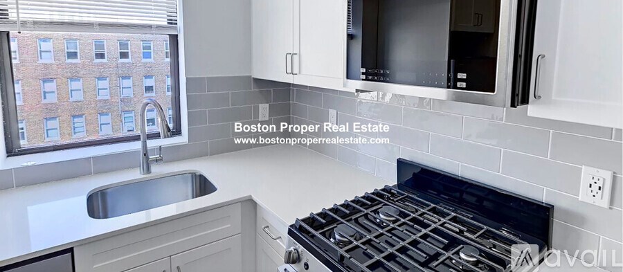A modern kitchen with a stove top oven and a window overlooking a building.