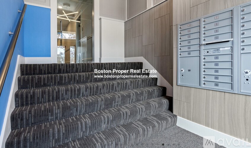 A staircase with a metal railing and a wall of mailboxes.