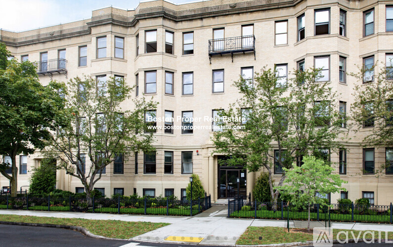 A large beige building with a black fence in front.