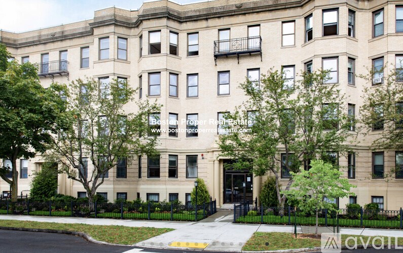 A large beige building with a black fence in front.