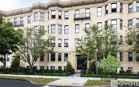 A large beige building with a black fence in front.