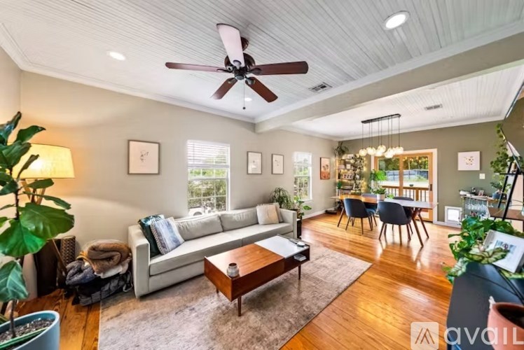 A living room with a white couch, a wooden coffee table, and a ceiling fan.