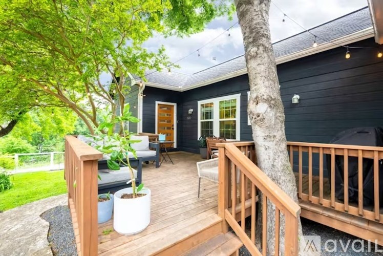 A wooden deck with a tree and a house in the background.