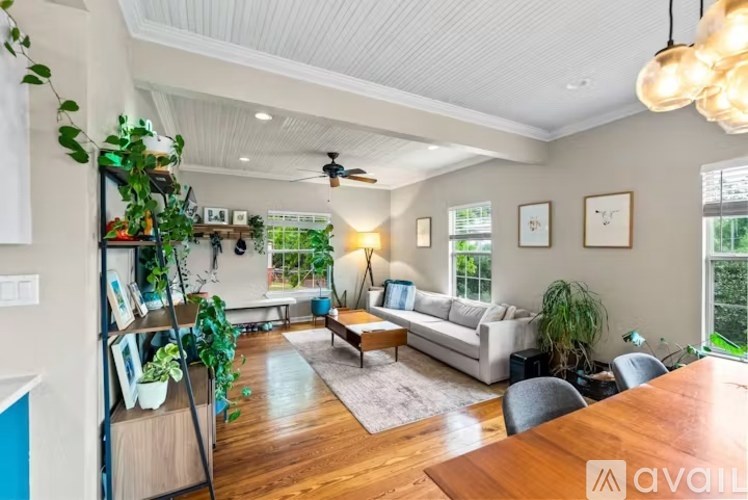 A living room with a white couch, a wooden table, and a ceiling fan.