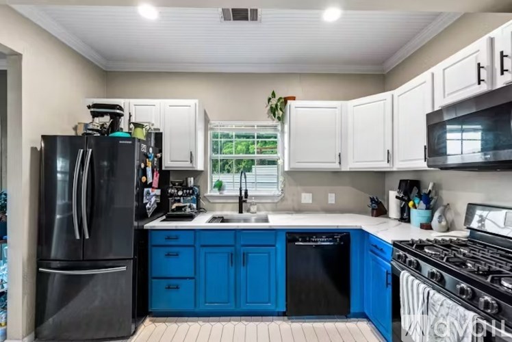 A kitchen with blue cabinets and a black refrigerator.