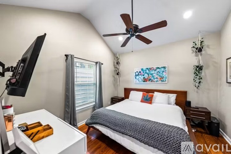 A bedroom with a bed, a television, and a ceiling fan.