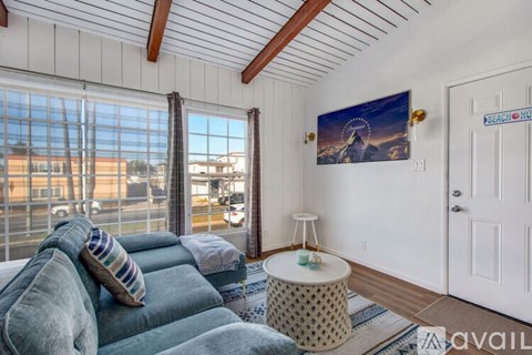 A living room with a blue couch and a painting on the wall.