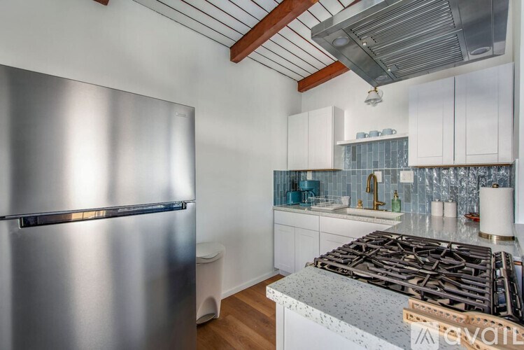 A modern kitchen with a stainless steel refrigerator and a stove top oven.