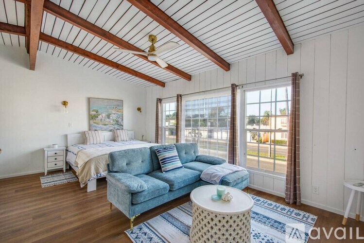 A bedroom with a blue couch and a wooden ceiling.