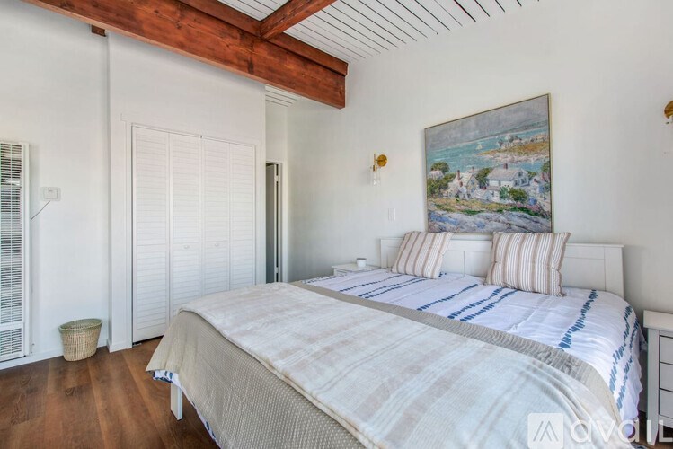 A bedroom with a large bed and a painting on the wall.