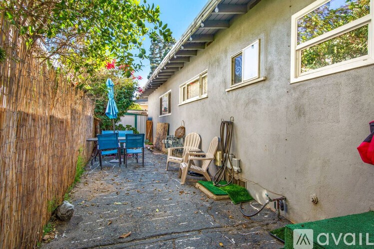 A patio with chairs and a table is surrounded by a wooden fence.