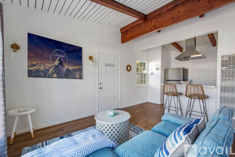 A living room with a blue couch and a painting of a mountain on the wall.