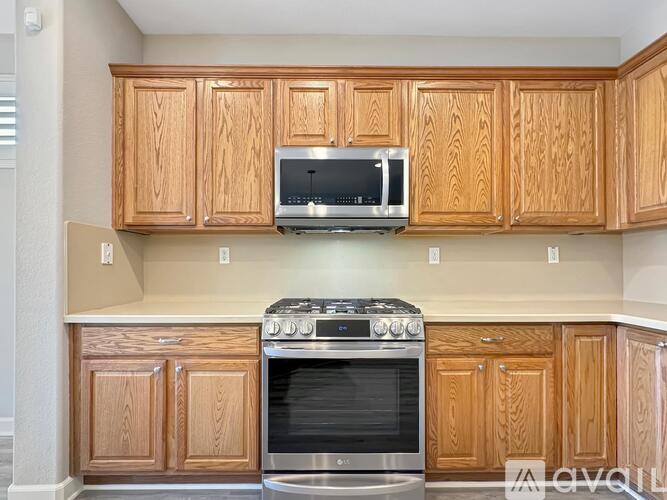 A kitchen with wooden cabinets and a stainless steel oven.