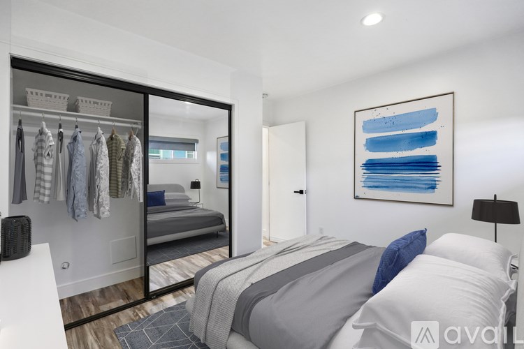 A bedroom with a large bed and a wardrobe with clothes hanging in it.