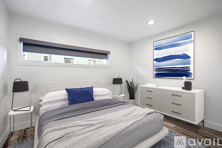 A bedroom with a bed, nightstand, and a painting on the wall.