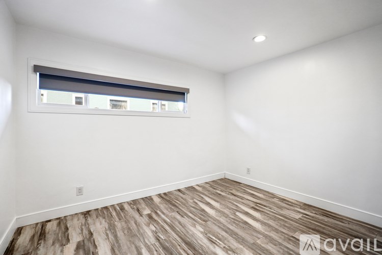 A room with wooden flooring and a window with blinds.