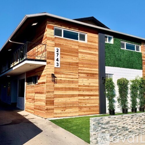A wooden house with a balcony and a green wall on the side.