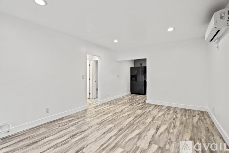 A spacious room with wood flooring and a wall-mounted air conditioner unit.