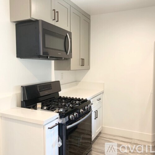 A black microwave oven is mounted above a black gas stove.
