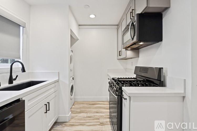 A modern kitchen with white cabinets and black appliances.
