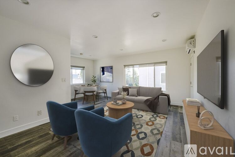 A living room with a blue chair and a television on the wall.