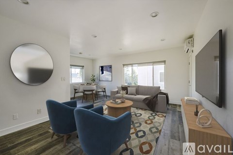 A living room with a blue chair and a television on the wall.