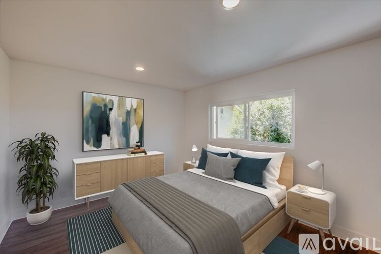 A bedroom with a bed, nightstand, and a painting on the wall.