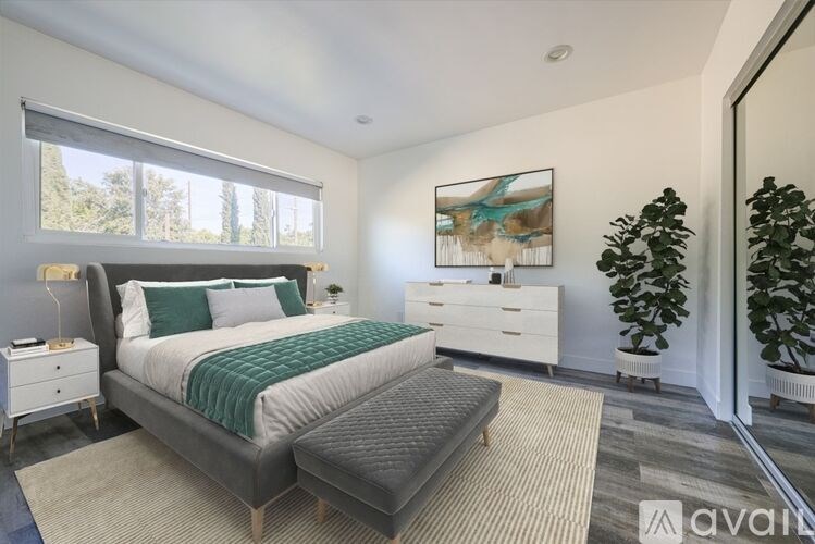 A bedroom with a large bed, a nightstand, and a painting on the wall.