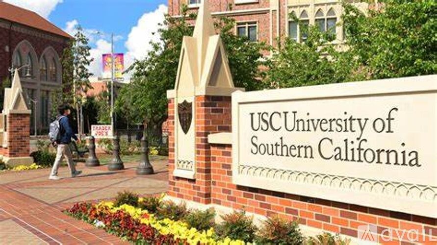 A person walks past a sign for the USC University of Southern California.