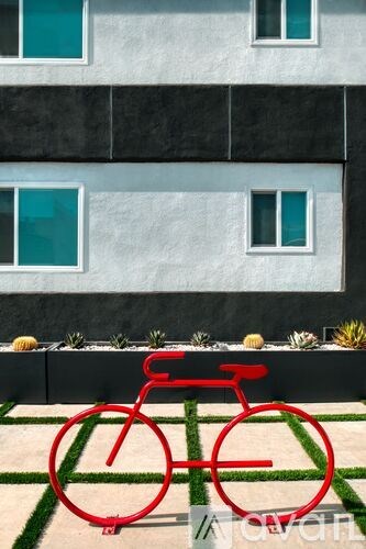 A red bicycle is drawn in the grass in front of a building.