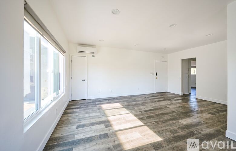 A spacious room with wooden flooring and white walls.