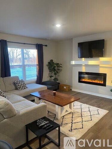 A living room with a fireplace and a television mounted above it.