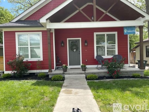 A red house with a porch and a sign that says "Highland".