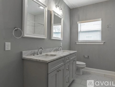A bathroom with a marble countertop and a large mirror above it.