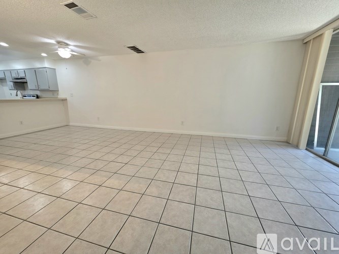 A spacious room with tiled flooring and a sliding glass door.