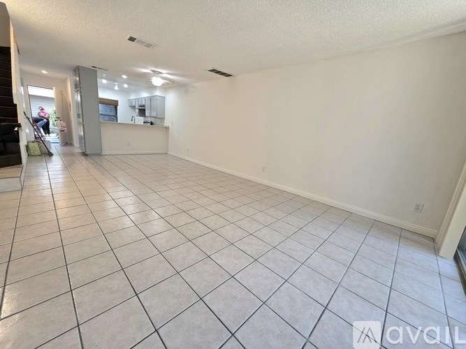 A spacious room with white tiled flooring and a reception desk in the background.