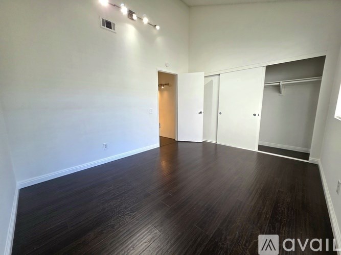 A room with wooden flooring and white walls, with a door and a closet visible.