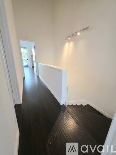 A hallway with wooden floors and white walls.