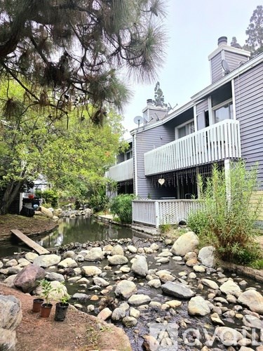 A grey house with a pond in front.