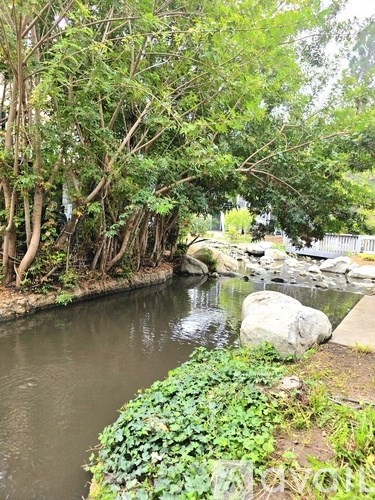 A river flows through a green landscape with trees and rocks.