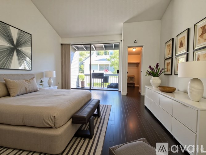 A bedroom with a large bed and a balcony overlooking a house.