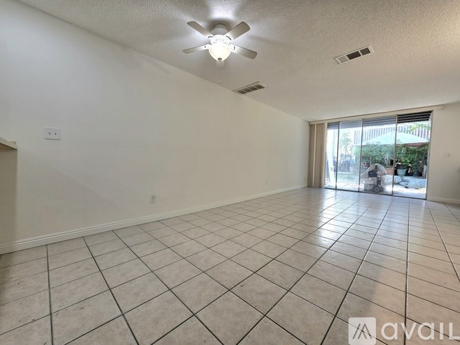 A spacious room with tiled flooring and a ceiling fan.