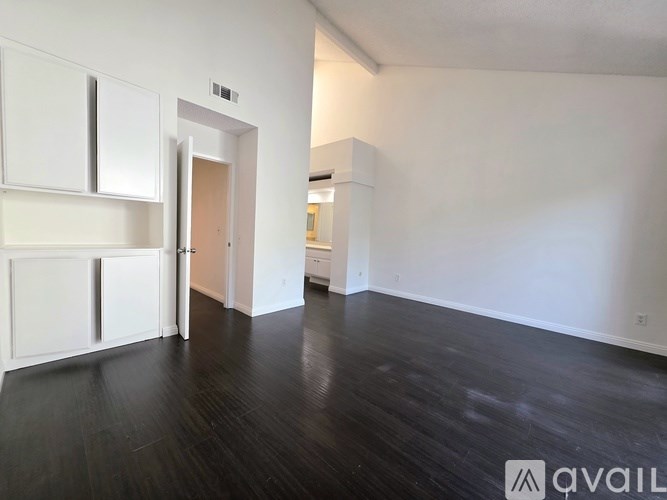 A room with white walls and dark wood flooring.