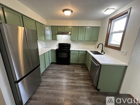 A kitchen with green cabinets and a stainless steel refrigerator.