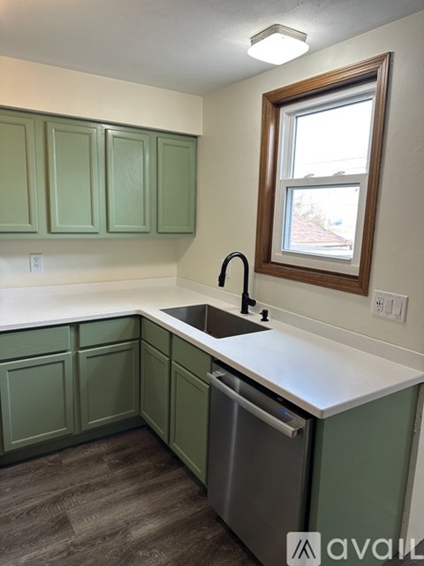 A kitchen with green cabinets and a window.