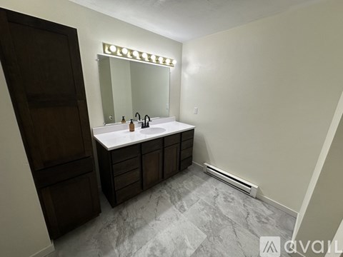 A bathroom with a marble floor and a mirror above the sink.