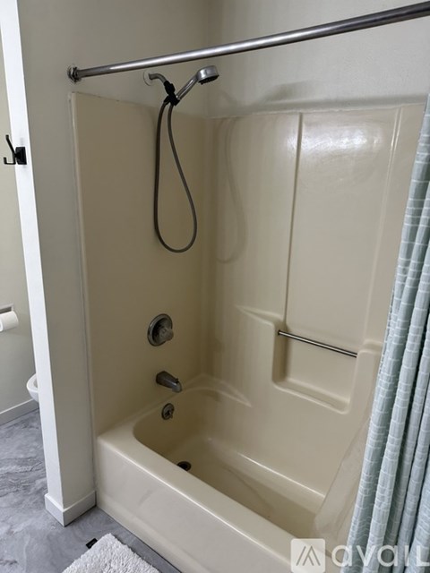 A white bathtub with a shower head and a curtain.
