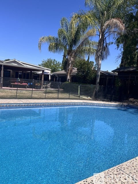 A pool surrounded by a fence and palm trees.